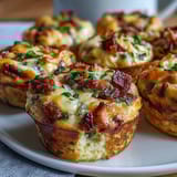 Freshly baked Breakfast Egg Muffins in a muffin tin, featuring fluffy eggs, cheese, and colorful veggies for a hearty snack.