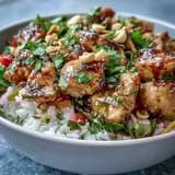 Thai Peanut Chicken Bowl with fluffy coconut rice, crisp veggies, and spicy peanut sauce drizzled on top.