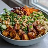 A close-up of a hearty Peanut Tofu Power Bowl with edamame, shredded purple cabbage, and chopped roasted peanuts for crunch.