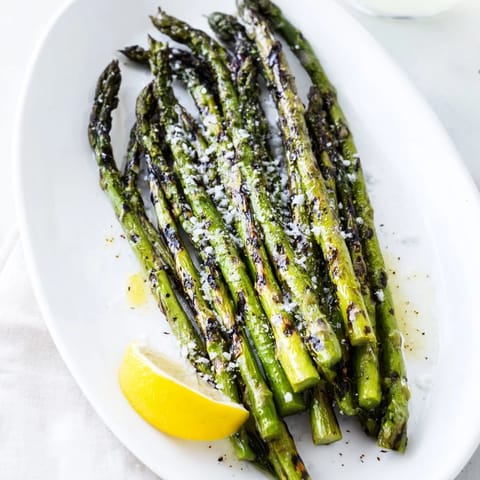 Tender green asparagus lightly charred on the grill, finished with flaky sea salt and served with lemon wedges.