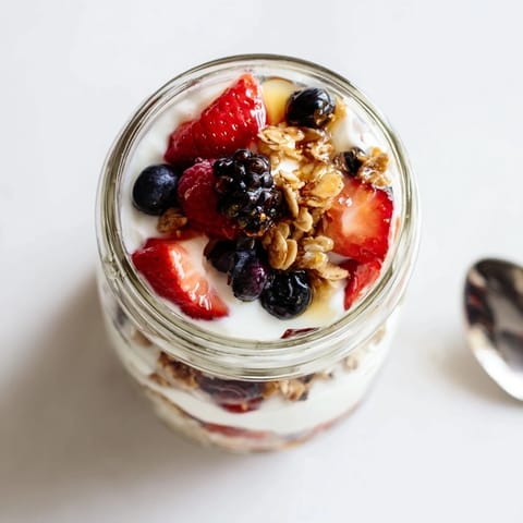 Freshly layered Berry Parfait with creamy Greek yogurt, crunchy granola, and vibrant berries in a glass.