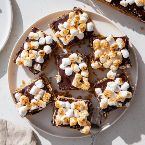 These S'mores Bars are served warm with gooey layers peeking out from a parchment-lined baking pan.