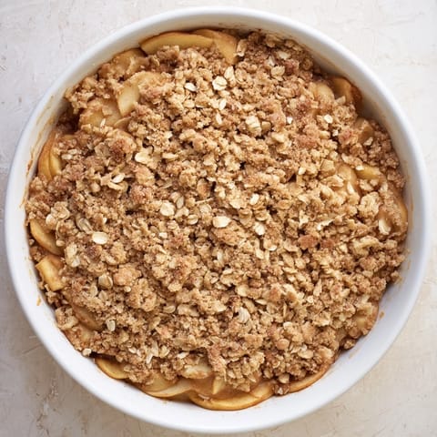 Warm Apple Crumble served in a rustic dish, ready to be scooped with vanilla ice cream.