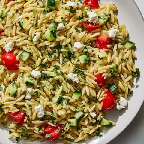 Bright Greek Orzo Salad with cherry tomatoes, cucumbers, red onion, feta, and lemon-oregano dressing.