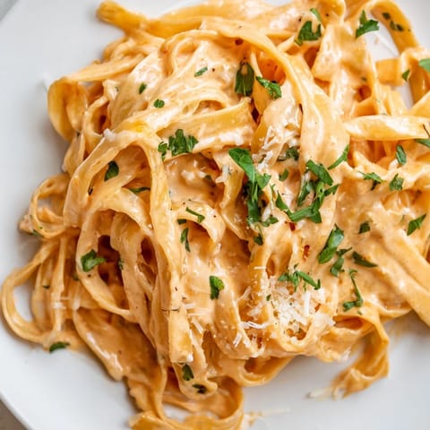 A bowl of vegetarian sriracha honey pasta garnished with fresh parsley and parmesan, perfect for a quick weeknight dinner.