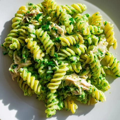 A serving of Cilantro Lime Chicken Pasta garnished with crumbled cotija cheese and fresh cilantro on a rustic wooden table.