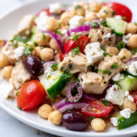 A close-up shot of a vibrant Mediterranean Chickpea Chicken Salad in a rustic bowl, highlighting colorful cherry tomatoes and fresh parsley garnish.  