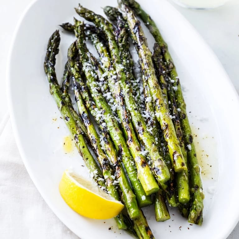 Tender green asparagus lightly charred on the grill, finished with flaky sea salt and served with lemon wedges.