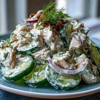 A vibrant bowl of Creamy Cucumber Chicken Salad features shredded chicken, crisp cucumbers, and red onion in a dill-yogurt dressing.  