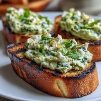 Creamy fava bean and mint bruschetta on smoky grilled sourdough, a spring appetizer.