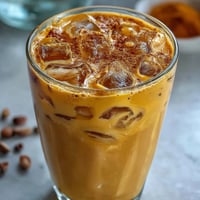 Vibrant Turmeric Golden Milk Iced Latte served refreshingly chilled with a sprinkle of cinnamon.